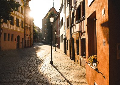 Leere Altstadtgasse im Gegenlicht, Fachwerk und warme Hausfassaden.