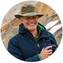 Dennis Weismantel mit Kamera, lächelnd im Freien – authentisches Portrait eines Fotografen