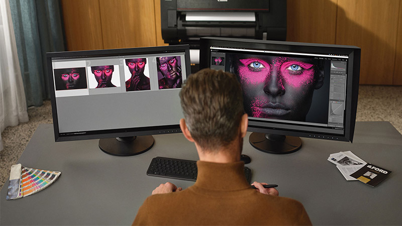 Präzises Farbmanagement mit EIZO Monitoren für Fotografen Fotograf bearbeitet Bild mit pinkfarbenem Make-up auf zwei EIZO Monitoren – professionelle Bildbearbeitung in höchster Farbtreue.
