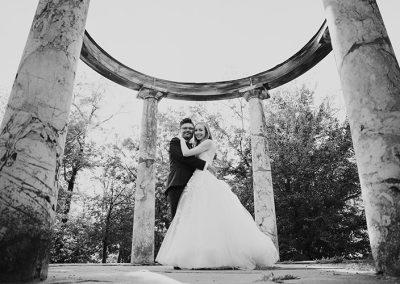 Brautpaar unter antiken Säulen, fotografiert von Dennis Weissmantel bei einer romantischen Hochzeit im Freien.