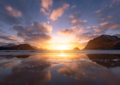 Farbenfroher Sonnenuntergang mit Spiegelung am Strand von Haukland, Norwegen.
