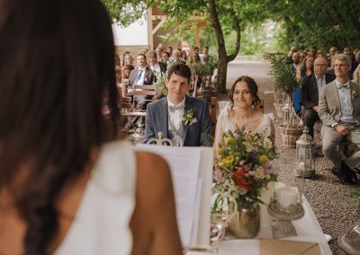 Brautpaar bei der Traurede unter freiem Himmel, aufgenommen von Hochzeitsfotograf Dennis Weissmantel.