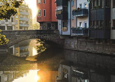 Häuser am Wasser spiegeln sich im Fluss bei Sonnenaufgang.