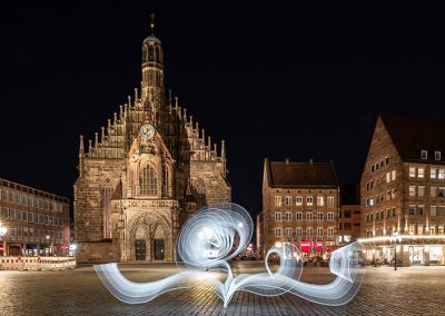 Frauenkirche Nürnberg bei Nacht mit geschwungenem weißem Lightpainting im Vordergrund.