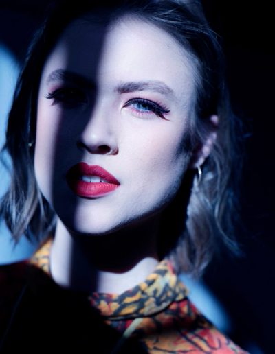 Frau mit rotem Lippenstift, hälftig im Schatten, starke Lichtkante im Gesicht.