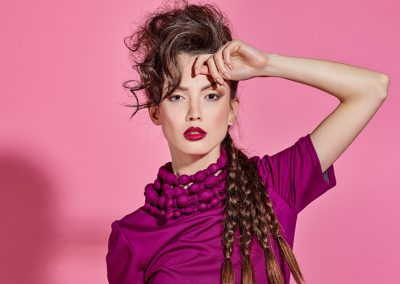 Frau in pinker Kleidung vor pinkem Hintergrund, ausdrucksstarkes Licht-Setup mit klaren Schatten