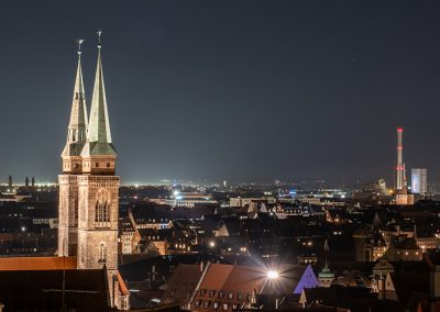 Blick auf die nächtliche Skyline Nürnbergs mit Kirchen und Stadtlichtern.