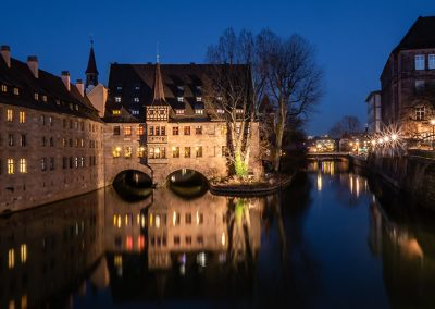 Nachtaufnahme vom Heilig-Geist-Spital in Nürnberg mit Spiegelung im Fluss.
