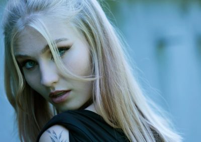 Frau mit Tattoo auf der Schulter schaut mit intensivem Blick zur Kamera.