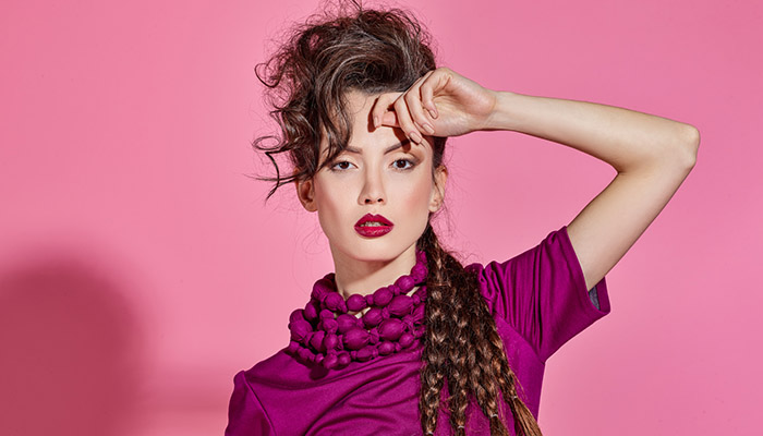 Frau in pinker Kleidung vor pinkem Hintergrund, ausdrucksstarkes Licht-Setup mit klaren Schatten