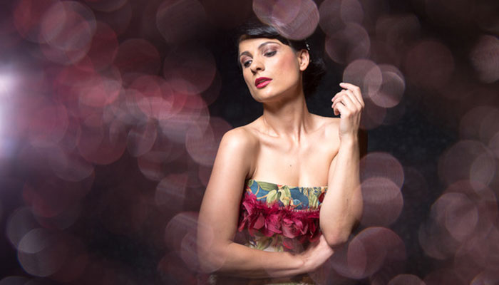Model in floralem Kleid, inszeniert mit dramatischem Bokeh-Hintergrund in warmen Tönen