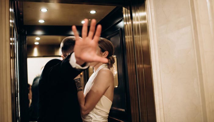 Person im Anzug verdeckt Kamera mit Hand – Symbolbild für Recht am eigenen Bild und Fotorecht