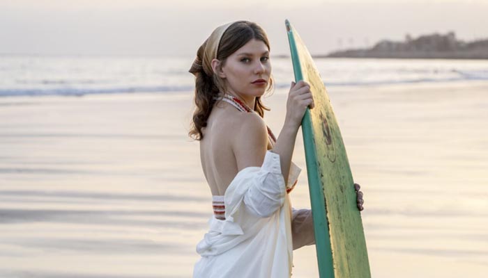 Junge Frau mit Surfbrett am Strand im Abendlicht – Porträt bei natürlichem Licht