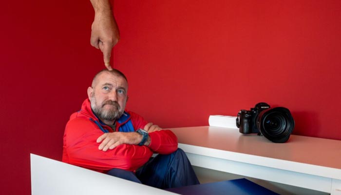 Fotograf sitzt nachdenklich in geöffneter Schublade – kreative Inszenierung mit Humor