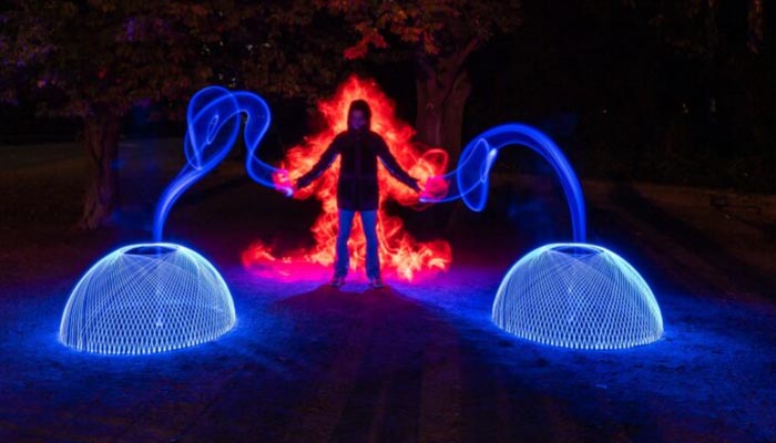 Leuchtende Lichtkreise in Blau und Rot – Lightpainting mit Figur im Zentrum bei Nacht