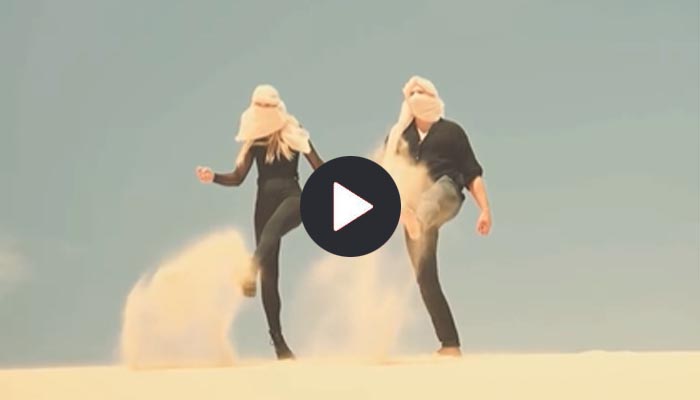 Eine Frau und ein Mann wirbeln Sand auf – Workshop Videografie mit spiegellosen Kameras bei Julia Schwegmann