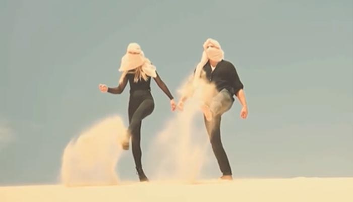 Eine Frau und ein Mann wirbeln Sand auf – Workshop Videografie mit spiegellosen Kameras bei Julia Schwegmann