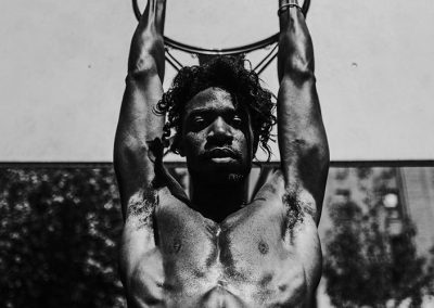 Sportlicher Mann hängt an einem Basketballkorb, dramatisch in Schwarz-Weiß fotografiert.